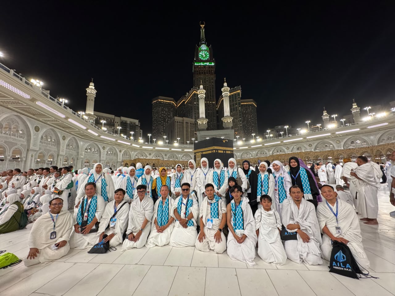 Jamaah Aila di Masjidil Haram dengan Ka'bah dan menara jam di belakang